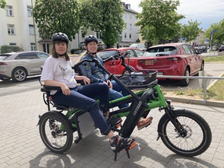 Zwei Frauen sitzen auf einem grünen Parallel-Tandem